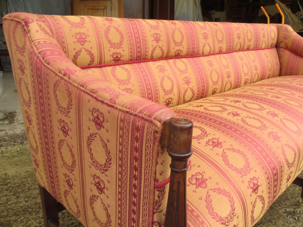 A Regency mahogany framed sofa upholstered in patterned red and gold fabric with reeded legs and brass castors. View IV