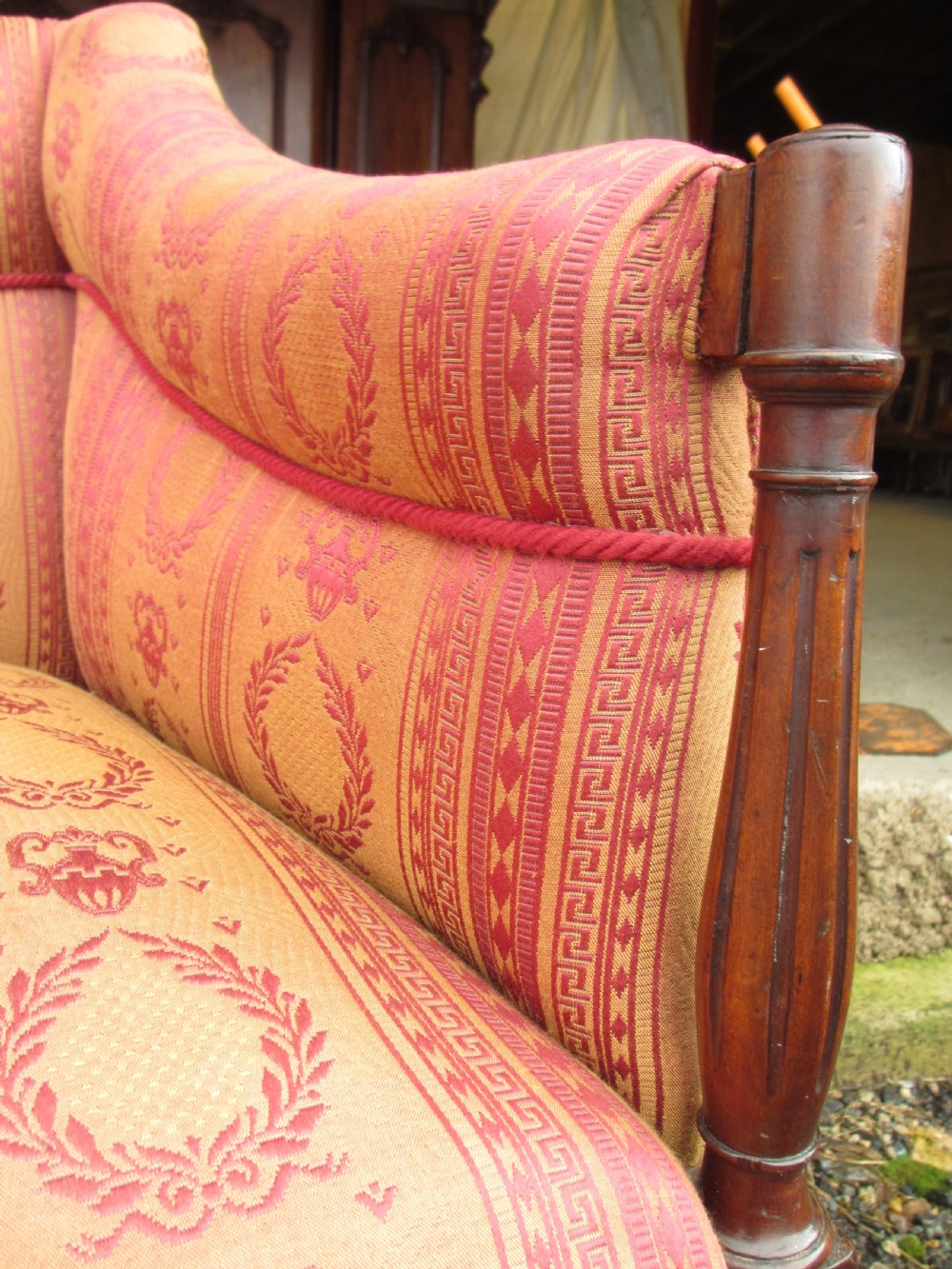 A Regency mahogany framed sofa upholstered in patterned red and gold fabric with reeded legs and brass castors. View V