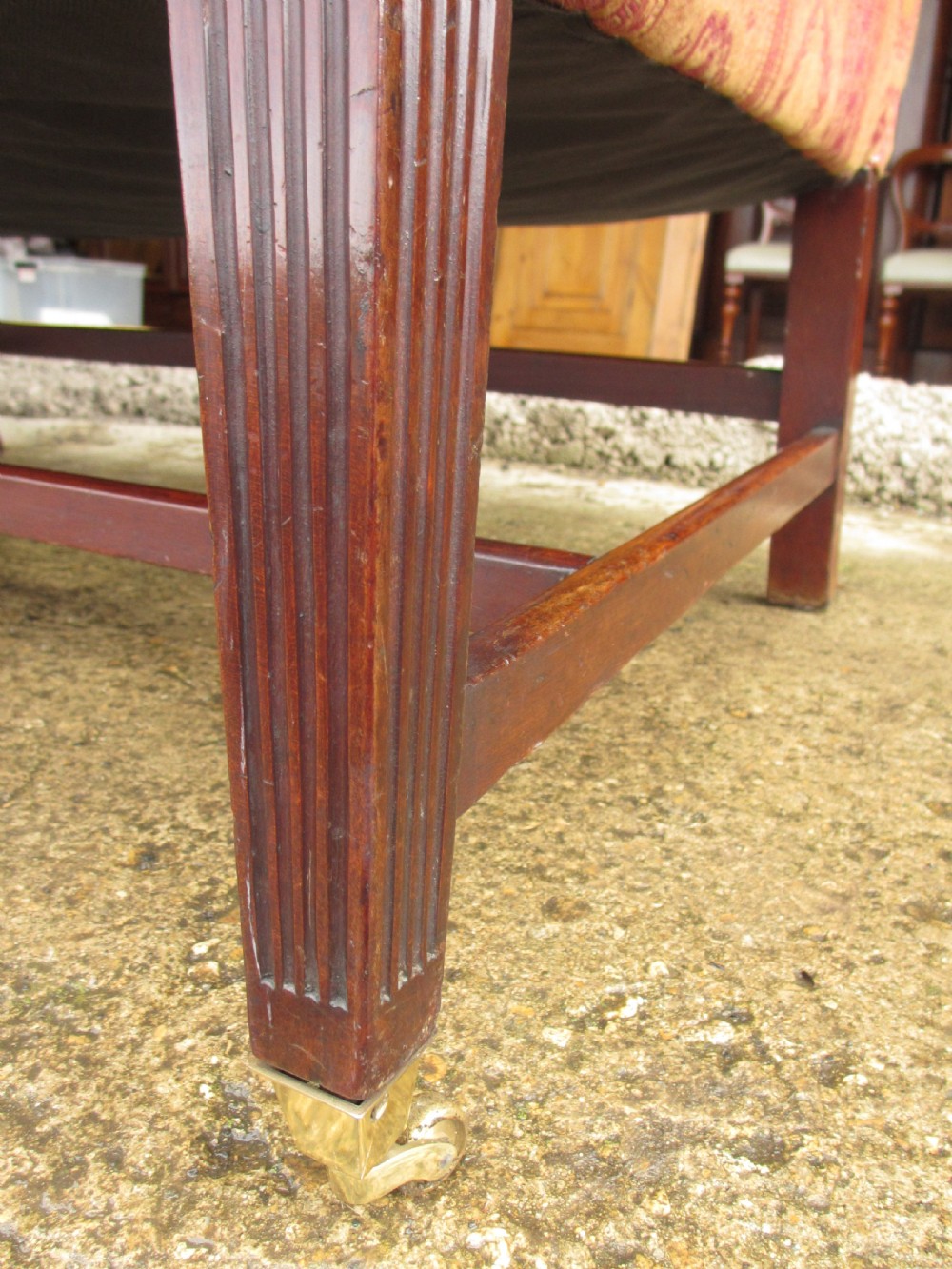 A Regency mahogany framed sofa upholstered in patterned red and gold fabric with reeded legs and brass castors. View VII