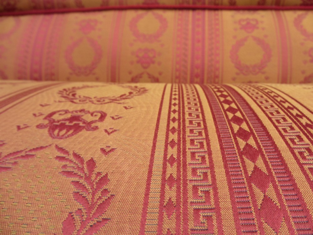 A Regency mahogany framed sofa upholstered in patterned red and gold fabric with reeded legs and brass castors. View XI