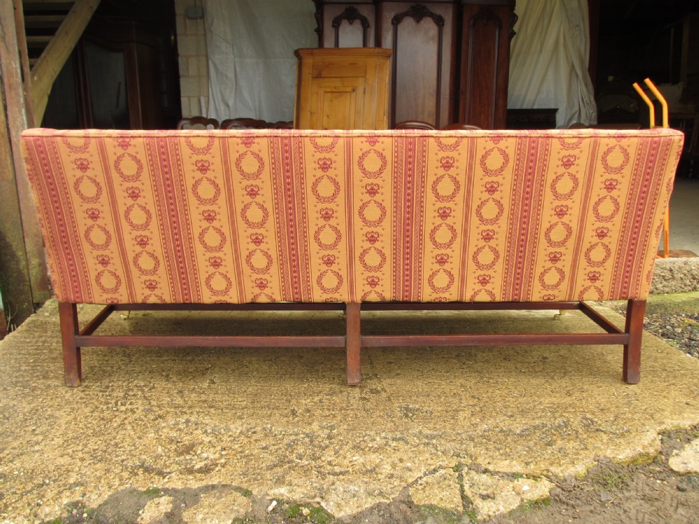A Regency mahogany framed sofa upholstered in patterned red and gold fabric with reeded legs and brass castors. View XIII