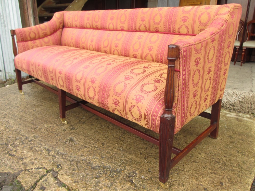 A Regency mahogany framed sofa upholstered in patterned red and gold fabric with reeded legs and brass castors. View XIV