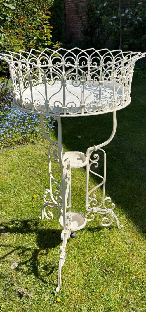 A nineteenth-century off-white painted wrought iron garden jardiniere featuring a tripod scrolled base and a lattice basket top. View IV