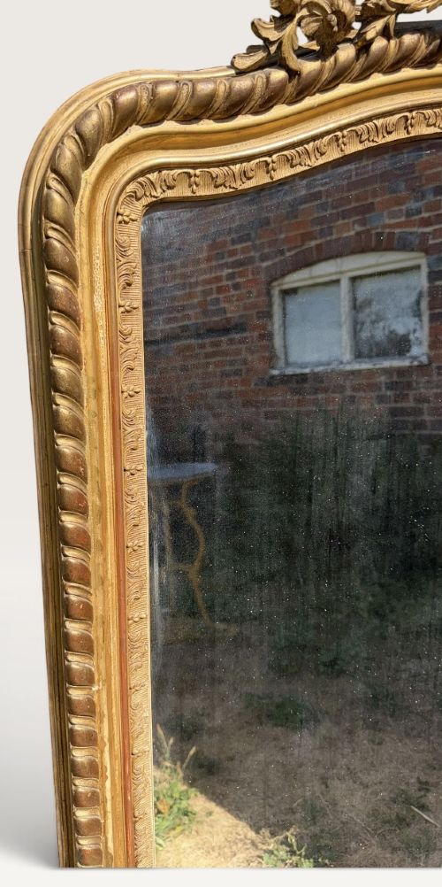 A 19th-century French giltwood overmantel mirror with an arched frame, rope twist moulding, and a central floral crest. View V