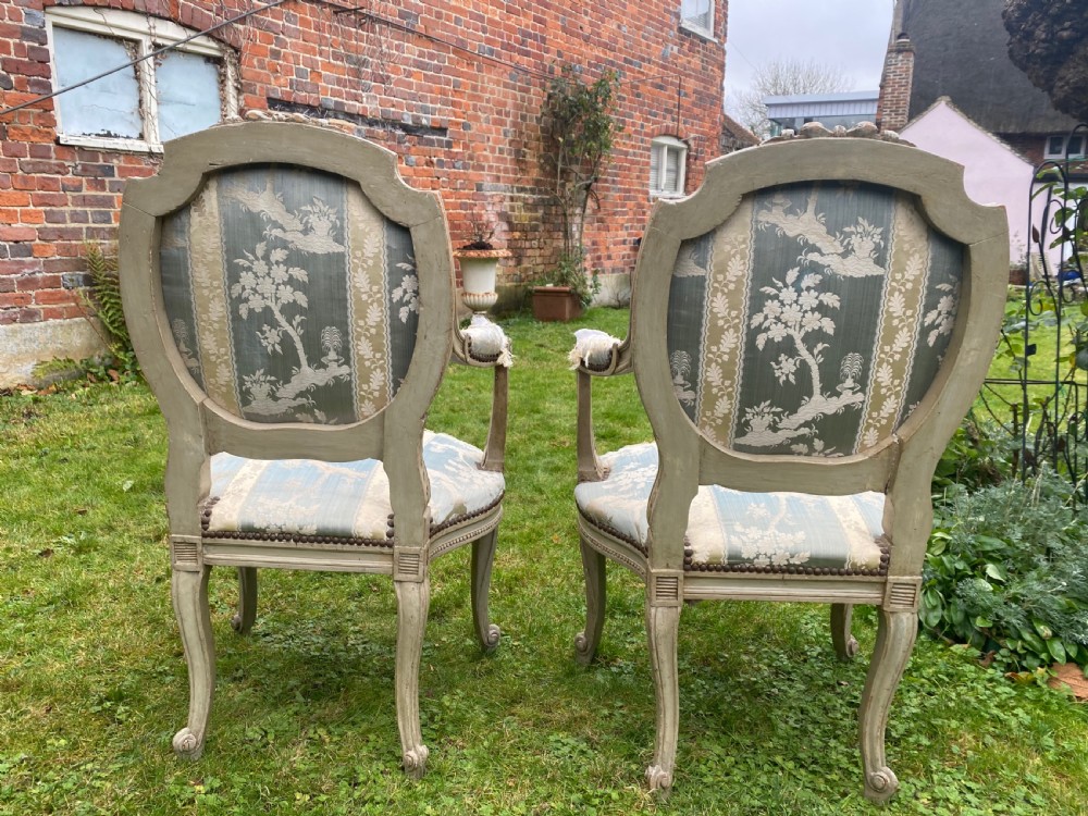 A pair of French style carved armchairs with distressed grey painted wooden frames and blue and cream patterned fabric upholstery. View III