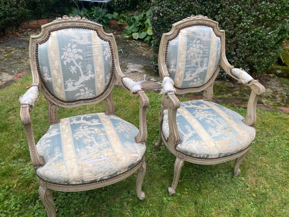 A pair of French style carved armchairs with distressed grey painted wooden frames and blue and cream patterned fabric upholstery. View IV
