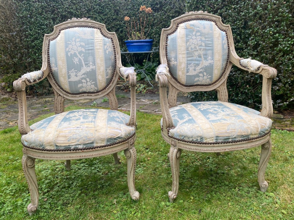 A pair of French style carved armchairs with distressed grey painted wooden frames and blue and cream patterned fabric upholstery. View V