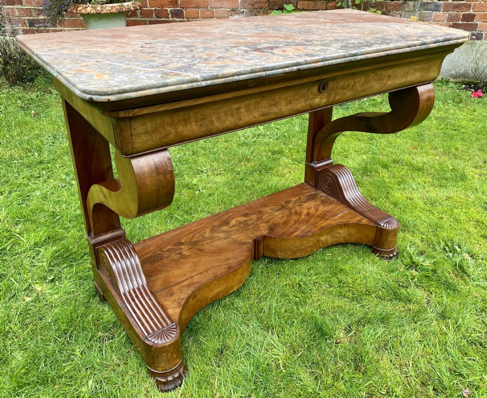 A 19th-century French Restauration figured walnut console table with a variegated grey marble top and S-scroll pedestal supports.