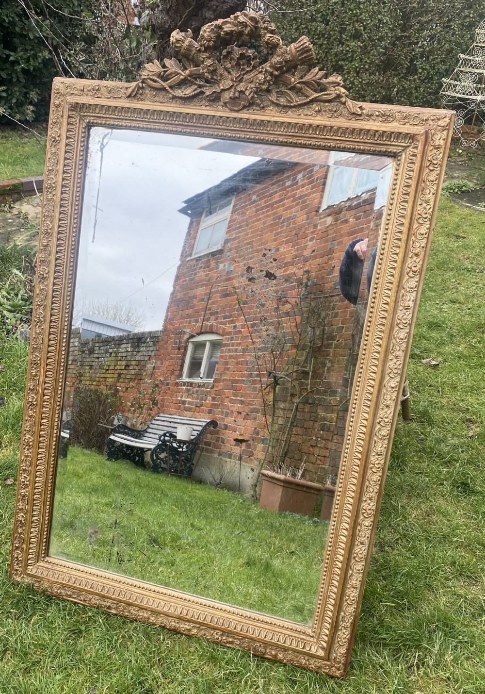 A large rectangular French giltwood mirror with a carved floral crest and beaded border.