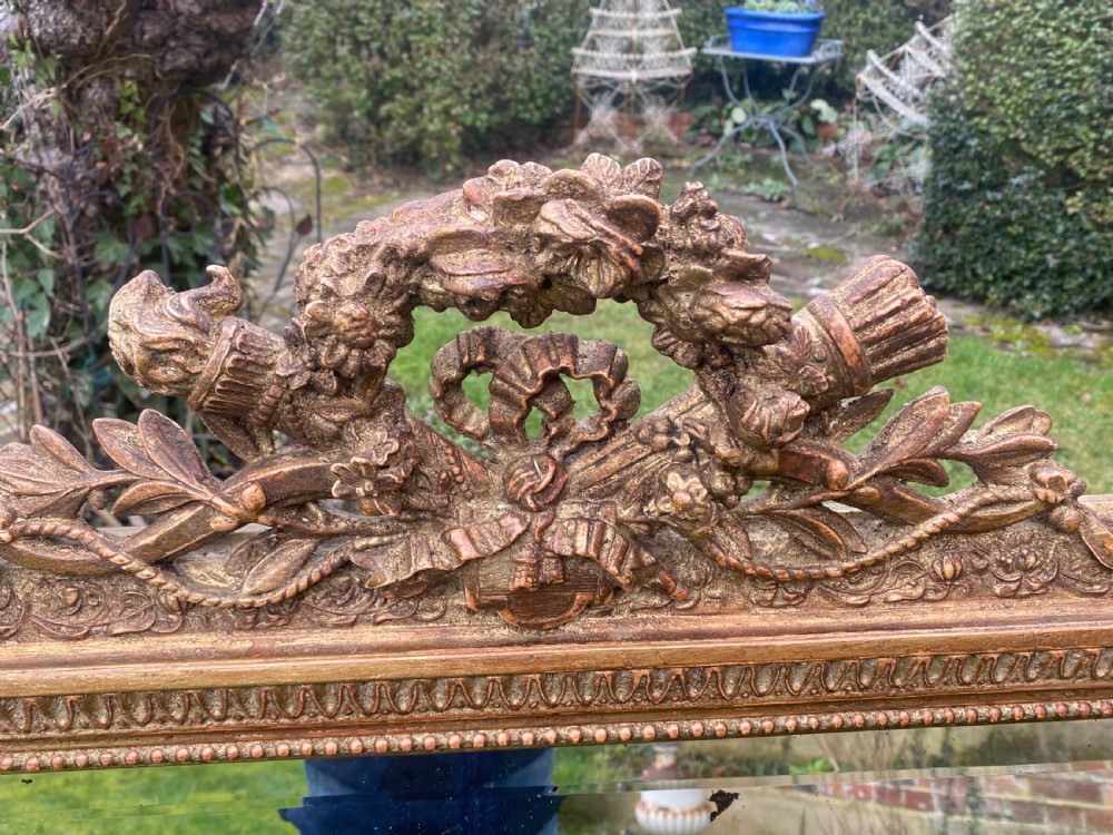 A large rectangular French giltwood mirror with a carved floral crest and beaded border. View II