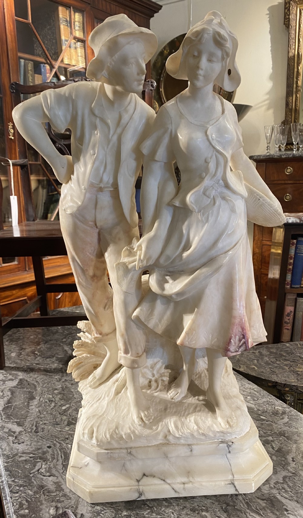 A large carved cream alabaster and marble sculpture depicting a young man and woman in rural clothing standing on a naturalistic base.