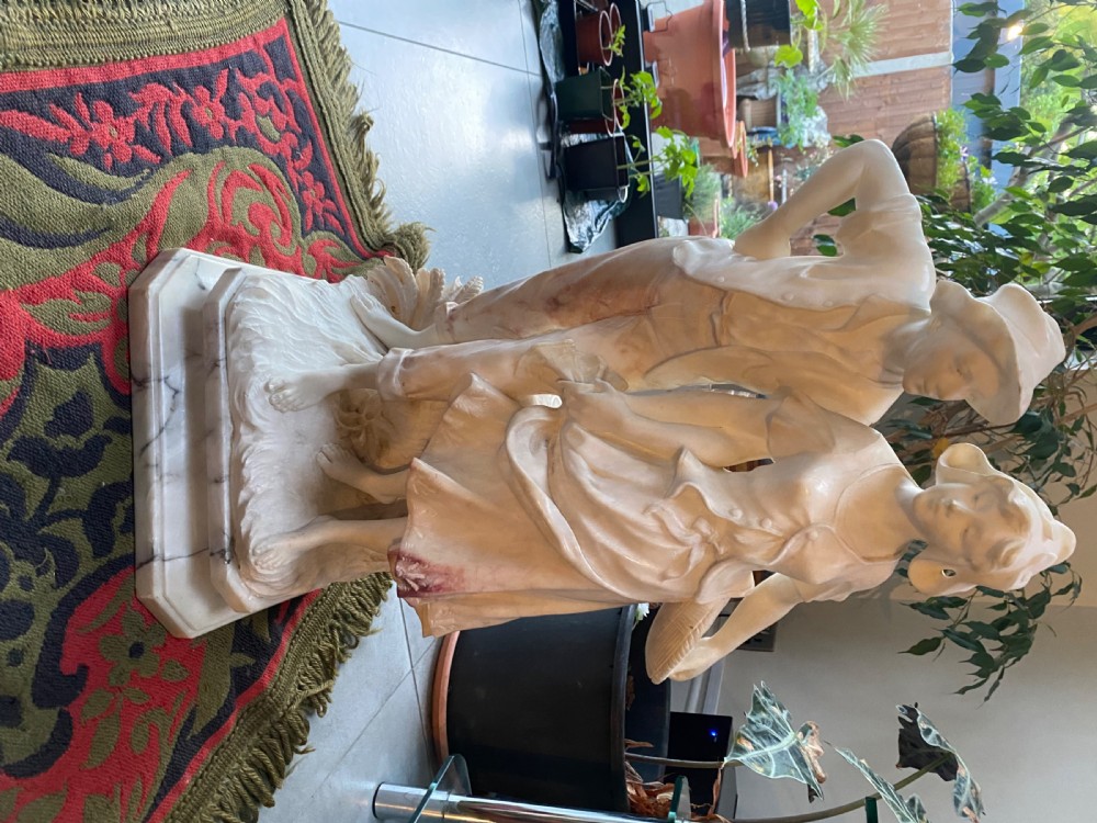 A large carved cream alabaster and marble sculpture depicting a young man and woman in rural clothing standing on a naturalistic base. View IV
