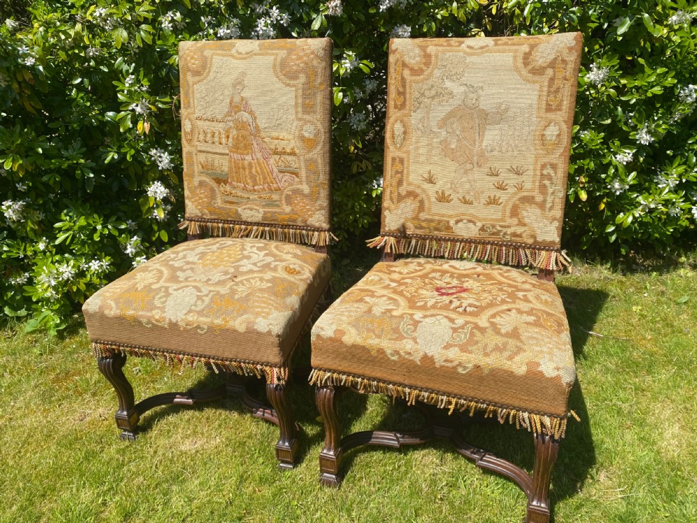 A pair of antique rosewood side chairs upholstered in detailed needlepoint fabric depicting figural scenes with fringed borders. View V