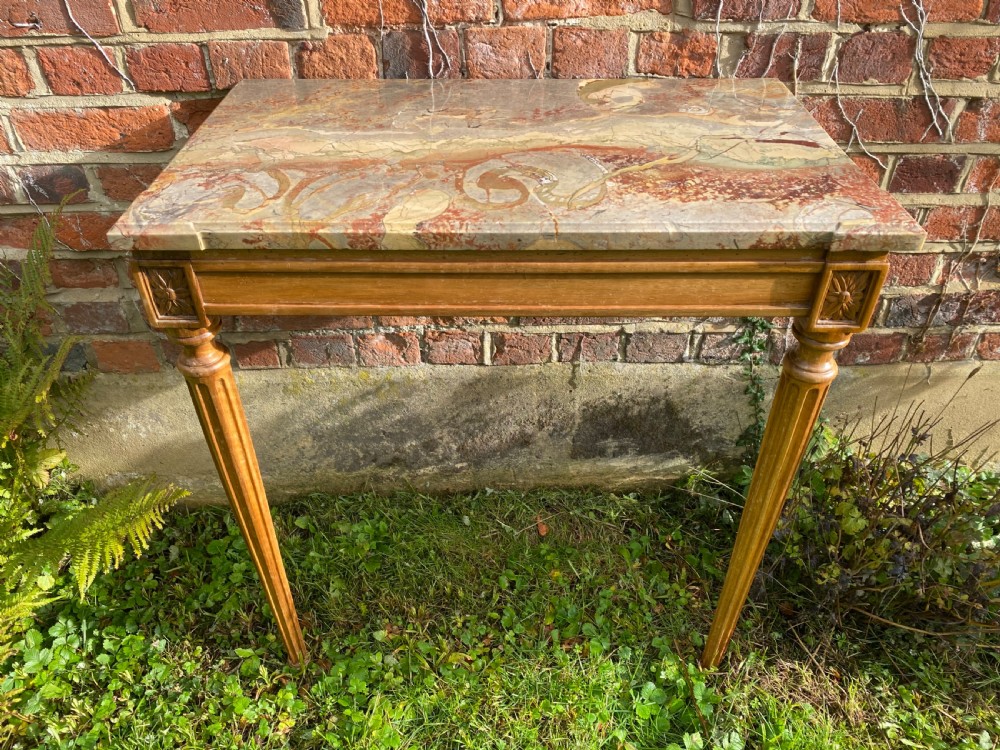 An 18th-century Neoclassical console table with a variegated marble top, carved apron, square corner rosettes, and fluted tapered legs.