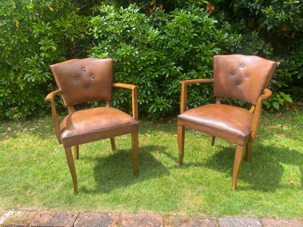 A pair of French Art Deco bridge armchairs with tan brown leather upholstery, diamond button-tufted backrests, and wooden frames. View VI