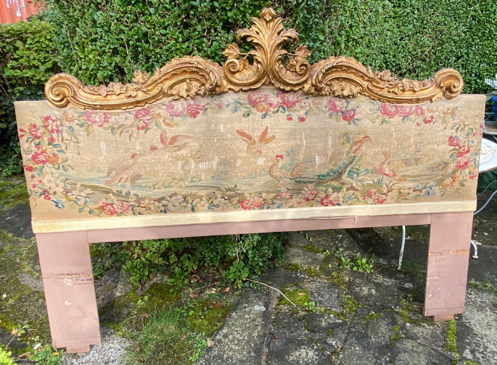 An expansive Venetian style headboard featuring a pictorial woven floral tapestry panel topped with an elaborately carved giltwood cresting. View II