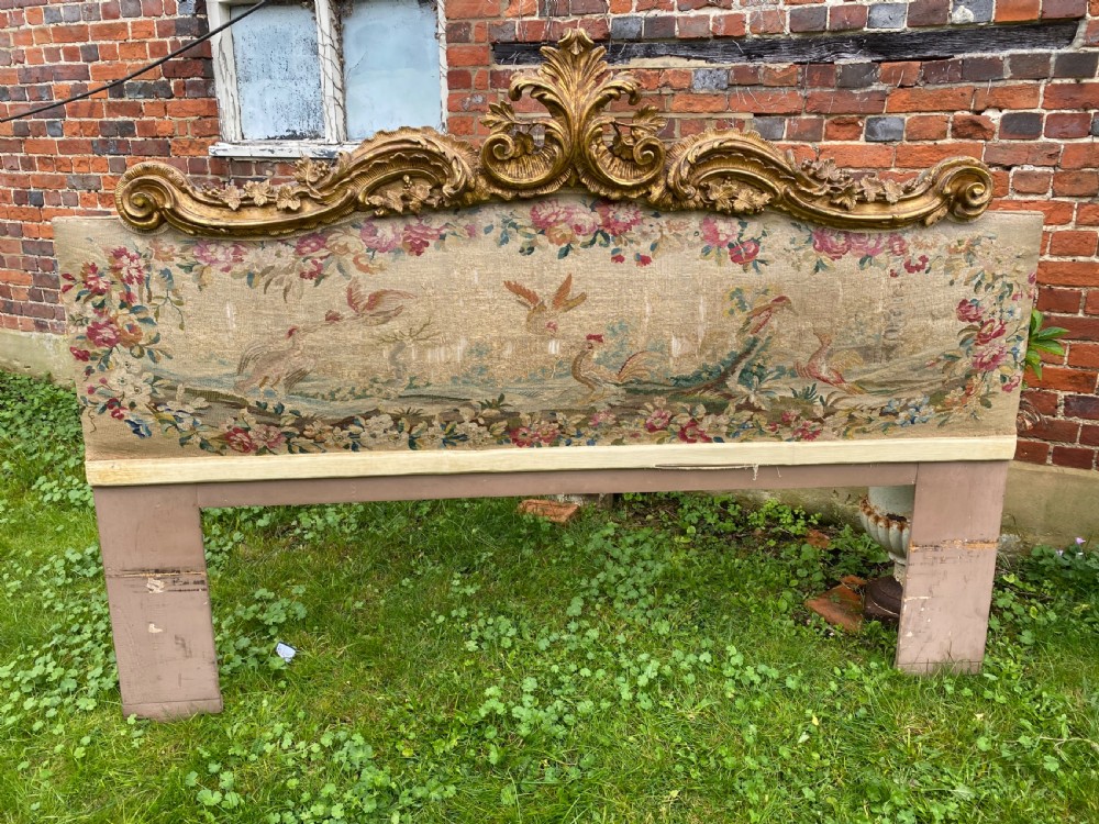 An expansive Venetian style headboard featuring a pictorial woven floral tapestry panel topped with an elaborately carved giltwood cresting. View VI
