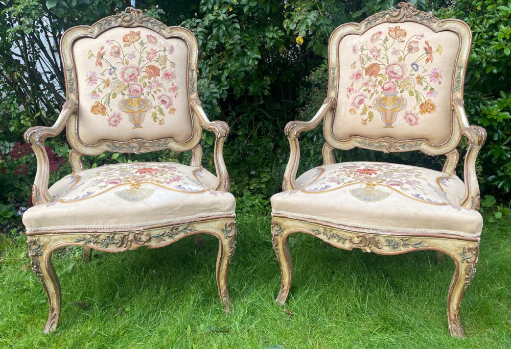 A pair of Italian Rococo style armchairs featuring cream-painted carved wooden frames and floral needlework upholstery depicting urns filled with flowers. View VI