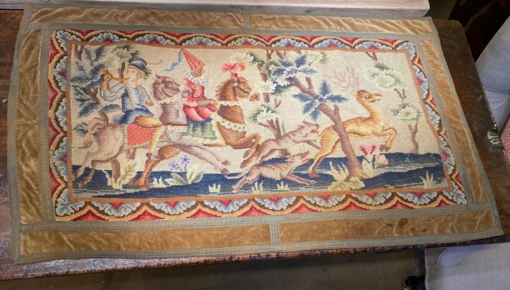 A rectangular early French needlepoint panel featuring a hunting scene with figures on horseback, hounds, and a stag within a velvet border. View IV