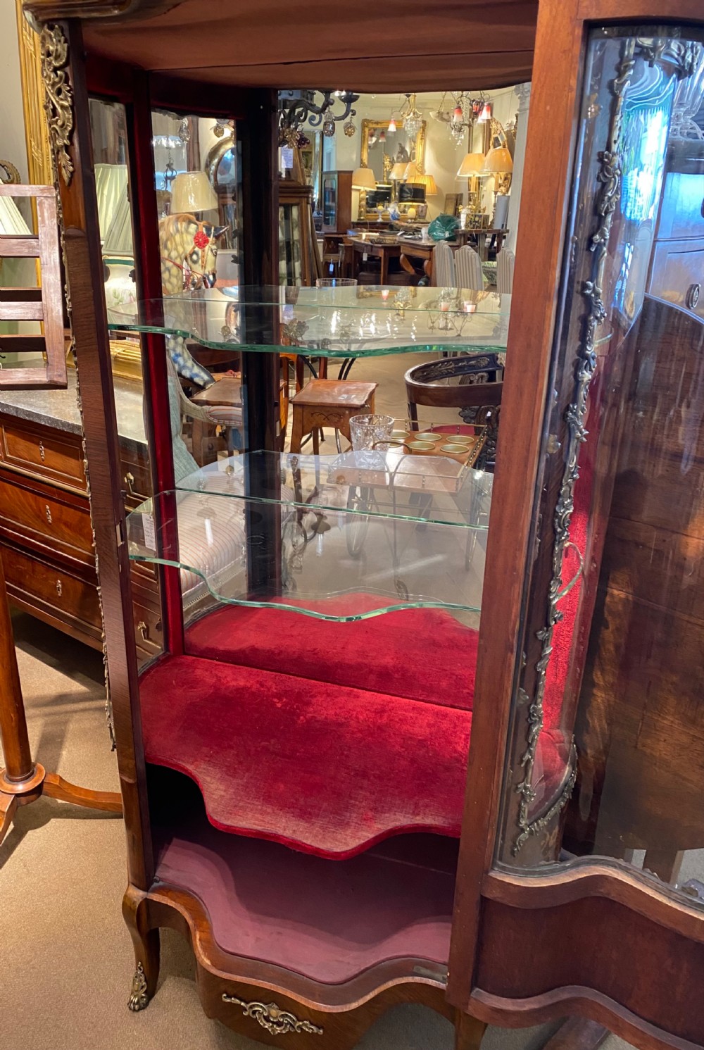 A French Rococo style serpentine glazed vitrine cabinet featuring dark wood veneer, intricate floral marquetry inlay on the lower panel, and decorative gilt bronze ormolu mounts. View VIII