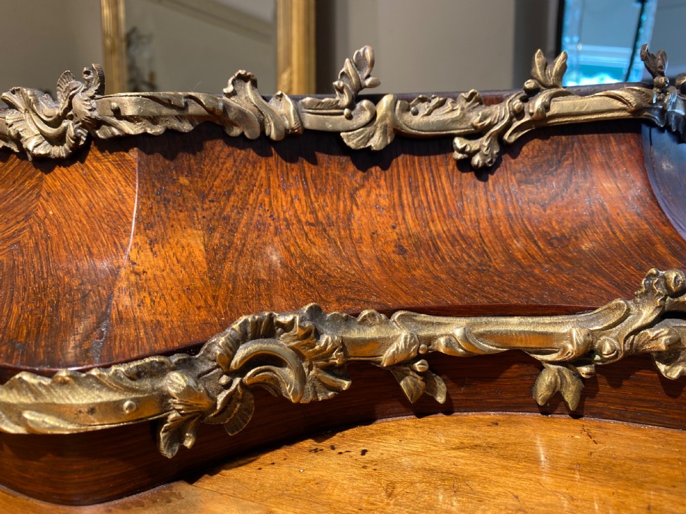 A French Rococo style serpentine glazed vitrine cabinet featuring dark wood veneer, intricate floral marquetry inlay on the lower panel, and decorative gilt bronze ormolu mounts. View X