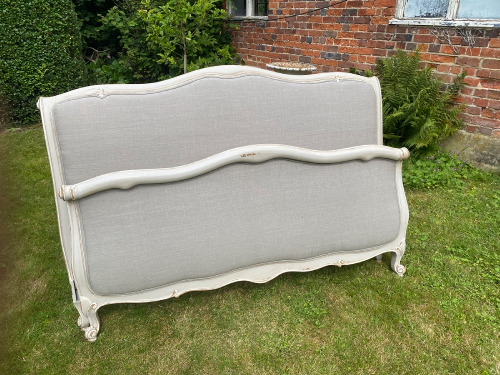 A French Louis XV style upholstered kingsize bed frame with a painted grey timber border and neutral linen fabric panels.