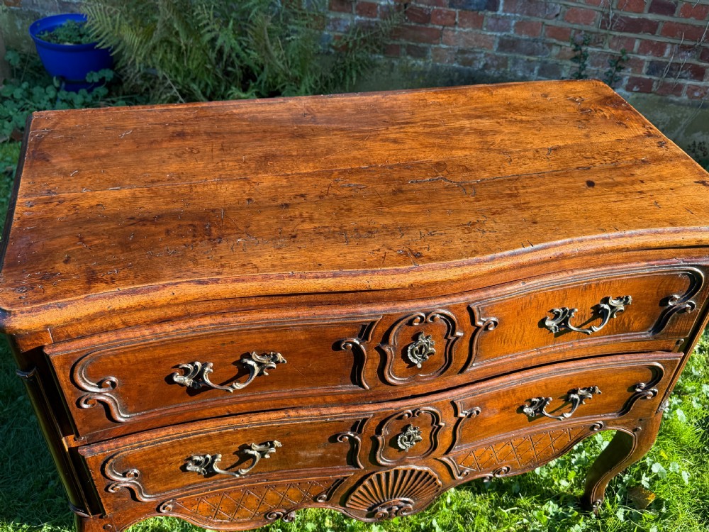 An 18th-century Rococo commode crafted from walnut, featuring two carved drawers with brass handles, cabriole legs, and a scallop shell carved into the lower apron. View II
