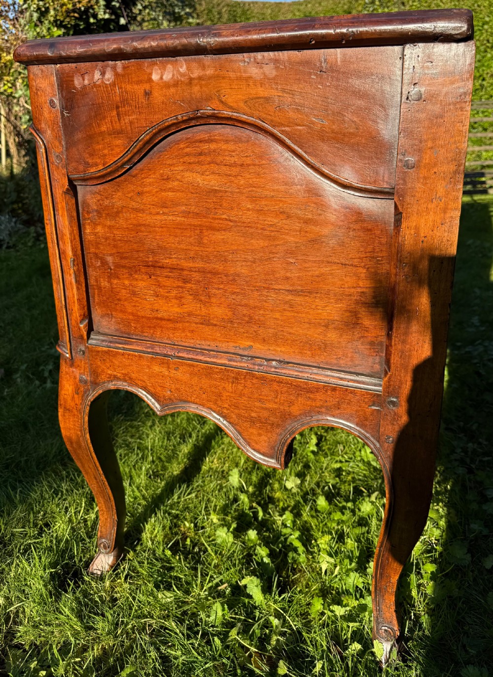 An 18th-century Rococo commode crafted from walnut, featuring two carved drawers with brass handles, cabriole legs, and a scallop shell carved into the lower apron. View III