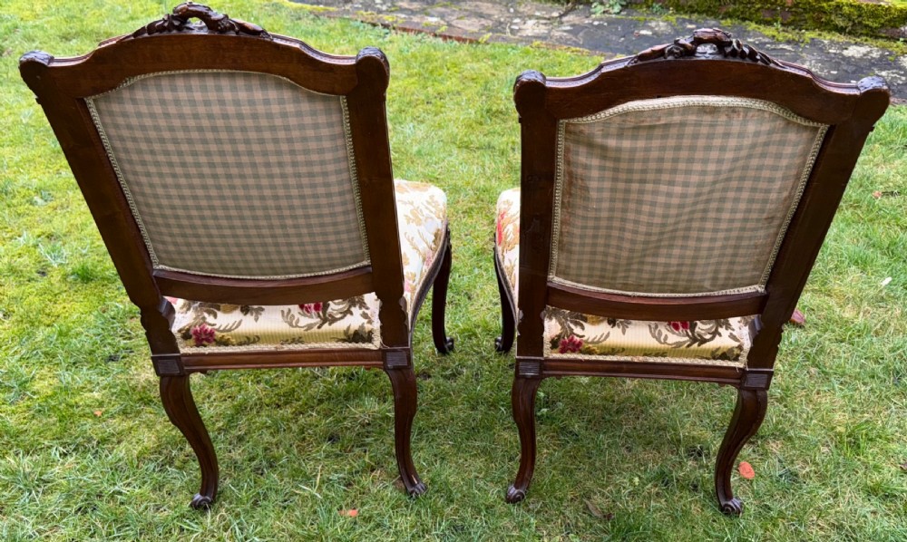 A pair of carved mahogany side chairs featuring cream floral velvet upholstery, cabriole legs, and detailed cresting carvings. View V