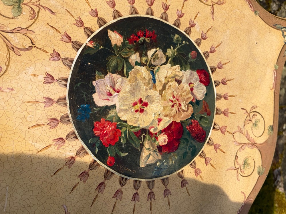 A cream-painted two-tier occasional table featuring cabriole legs, a shaped serpentine top with a floral central medallion, and decorative scrollwork borders. View II