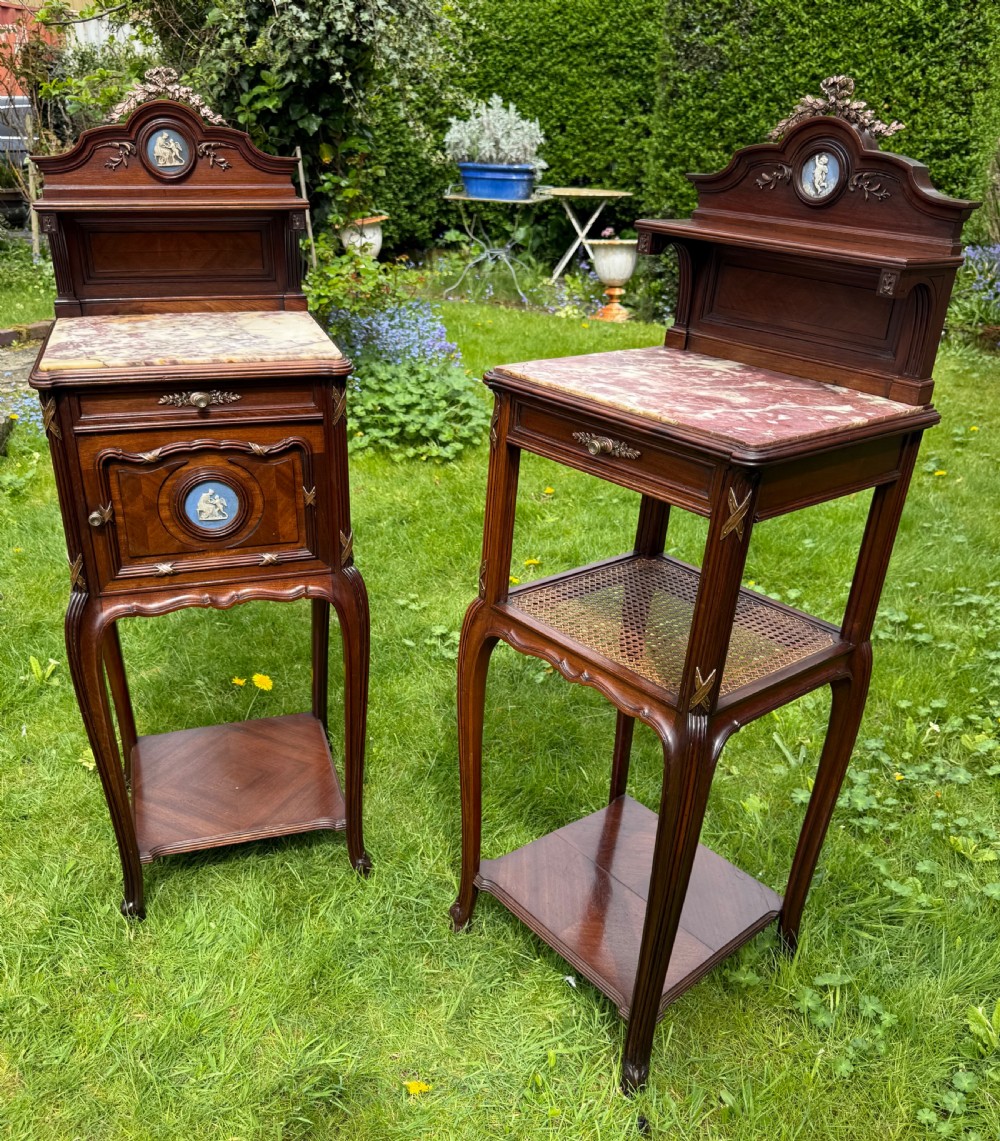 A pair of French Neoclassical wooden bedside tables featuring red marble tops, ceramic medallion inserts, Ormolu mounts, curved legs, and lower open shelves.