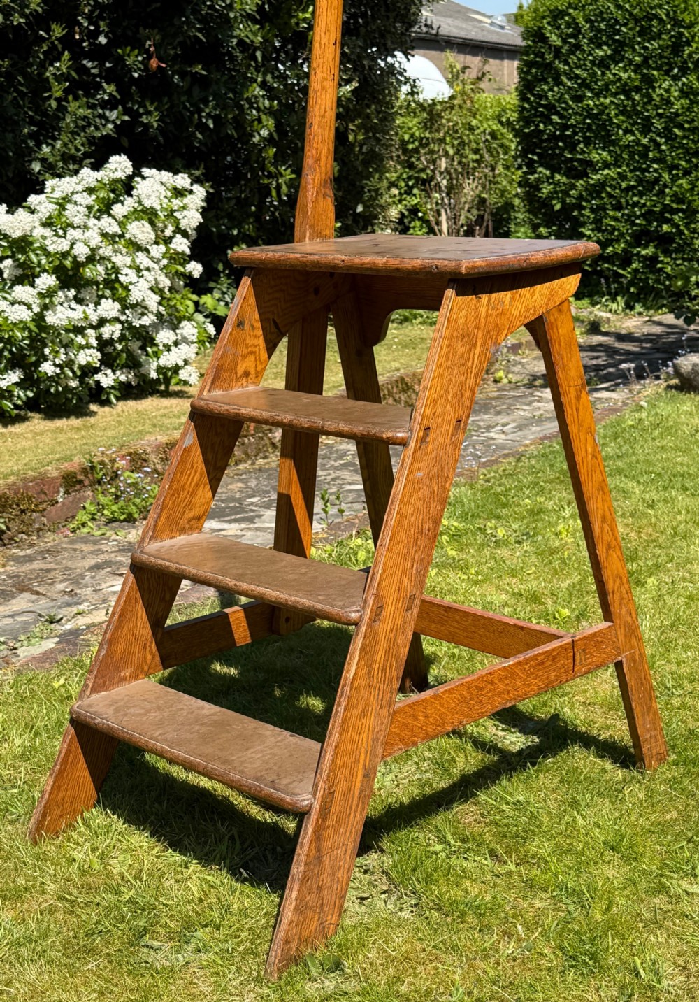 A solid oak library step ladder featuring four treads and a tall vertical handrail pole set on an A-frame structure. View II