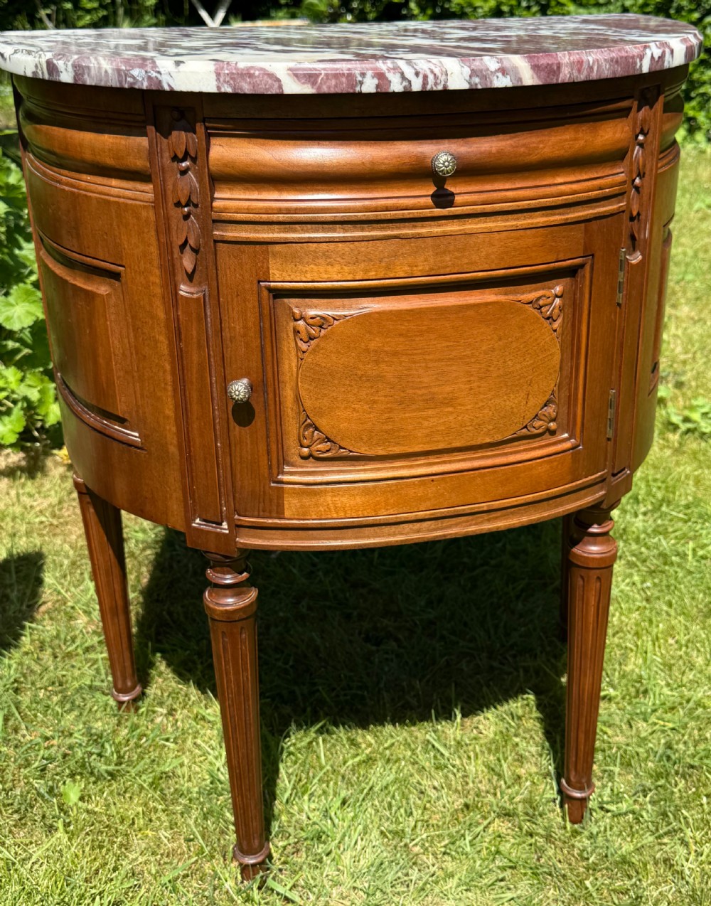 Pair of semi-circular walnut bedside cabinets with carved door panels, fluted legs, and variegated marble tops. View II