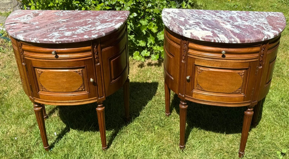 Pair of semi-circular walnut bedside cabinets with carved door panels, fluted legs, and variegated marble tops. View V