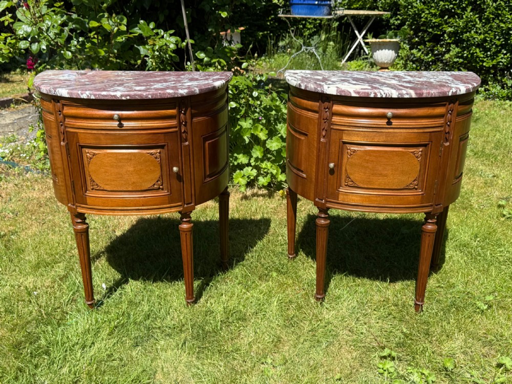 Pair of semi-circular walnut bedside cabinets with carved door panels, fluted legs, and variegated marble tops. View VI
