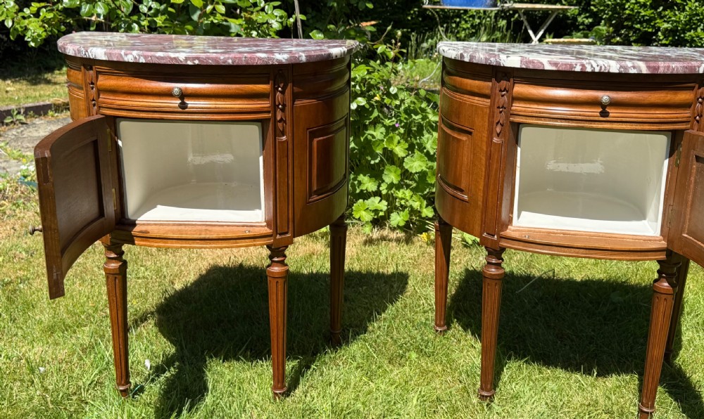 Pair of semi-circular walnut bedside cabinets with carved door panels, fluted legs, and variegated marble tops. View VII