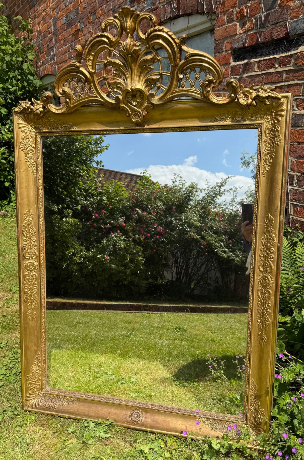 A large rectangular French Restauration giltwood mirror featuring elaborate scroll cresting and decorative corner moulding. View V