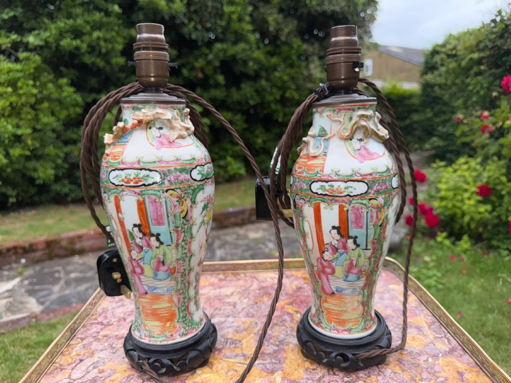 A pair of 19th-century Chinese Famille Rose porcelain vase-form table lamps decorated with colourful figures and foliage, mounted on carved dark wooden bases. View V