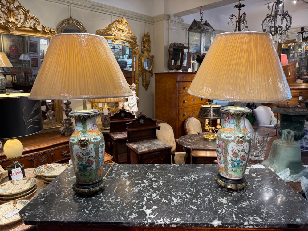 A pair of 19th-century Chinese Famille Rose porcelain vase lamps featuring detailed hand-painted figural scenes, brass mounts, and carved dark wood bases. View VIII
