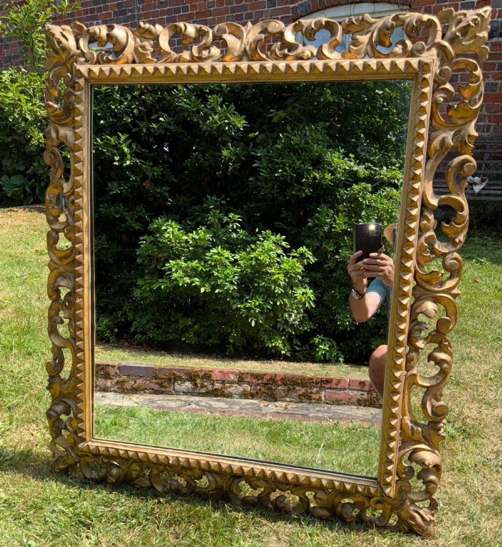A large rectangular wall mirror featuring an intricate hand-carved gold giltwood frame with openwork acanthus foliage and a notched inner border. View III