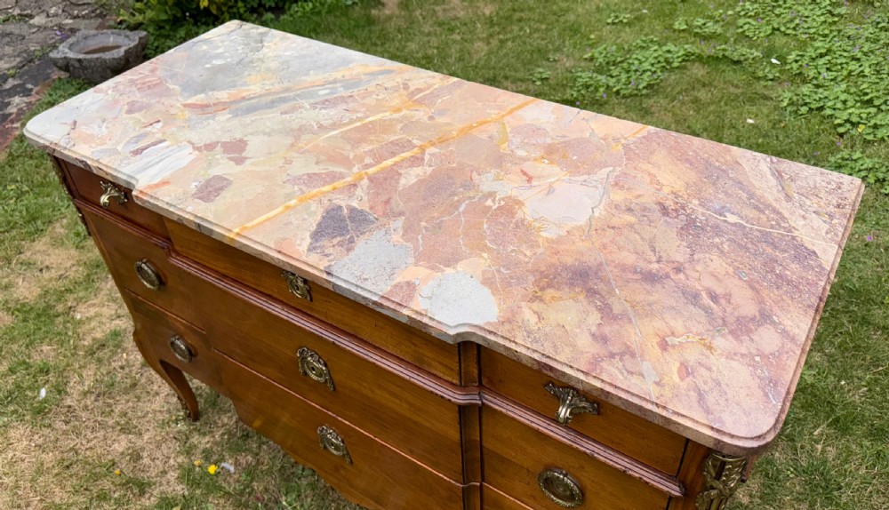 A French Transitional style cherrywood commode featuring a contoured marble top, decorative brass mounts, and cabriole legs. View II