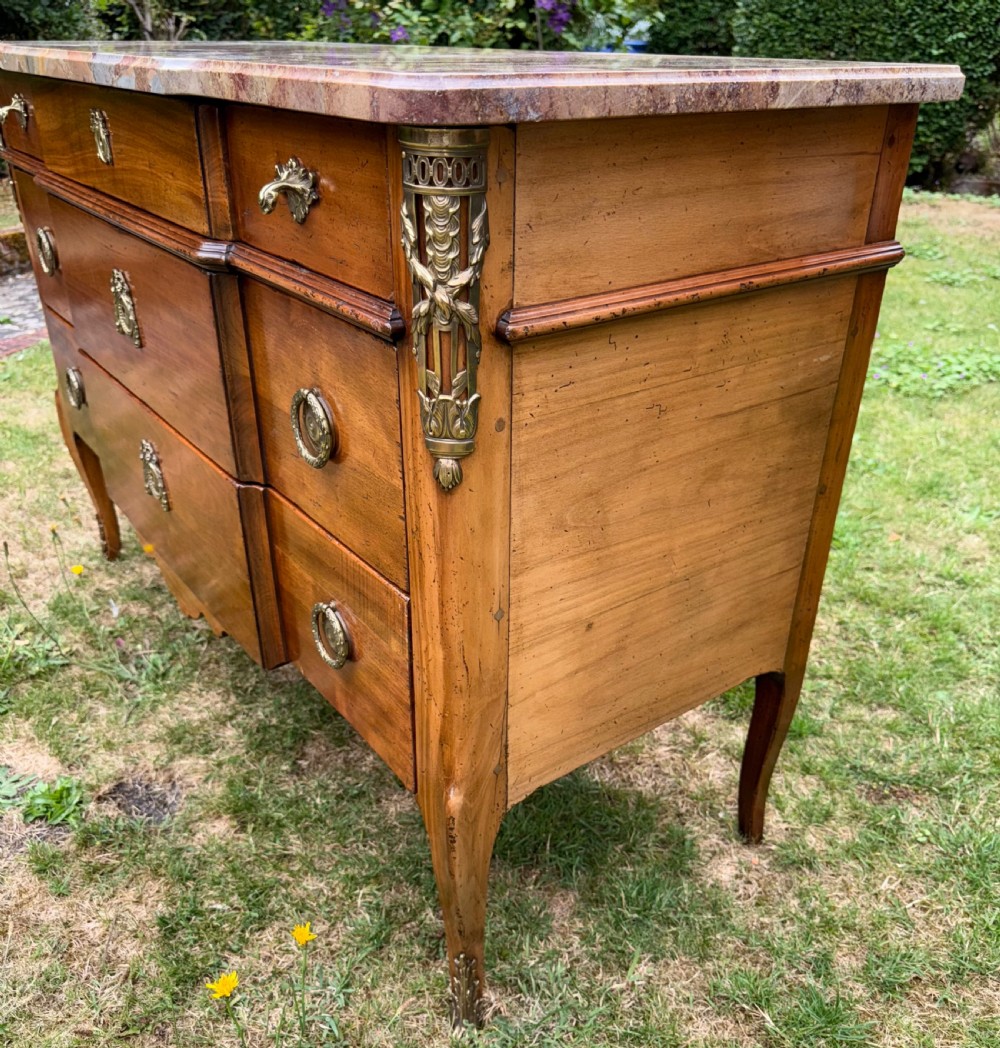 A French Transitional style cherrywood commode featuring a contoured marble top, decorative brass mounts, and cabriole legs. View VI
