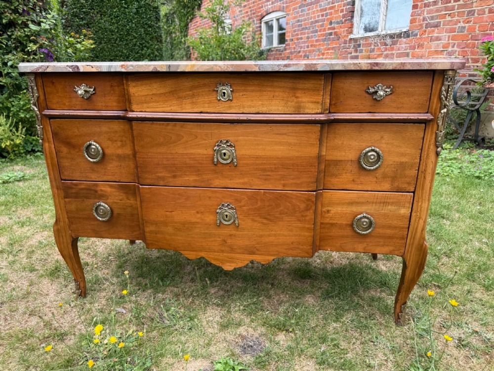 A French Transitional style cherrywood commode featuring a contoured marble top, decorative brass mounts, and cabriole legs. View VII