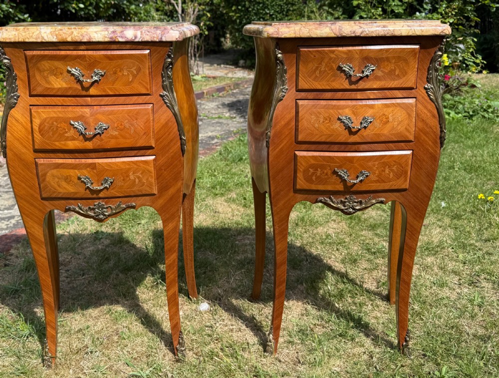 A pair of French Louis XV style marquetry bedside tables featuring marble tops, three floral inlaid drawers, gilt bronze mounts, and slender cabriole legs. View II