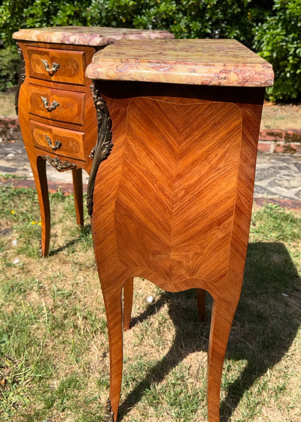 A pair of French Louis XV style marquetry bedside tables featuring marble tops, three floral inlaid drawers, gilt bronze mounts, and slender cabriole legs. View VII