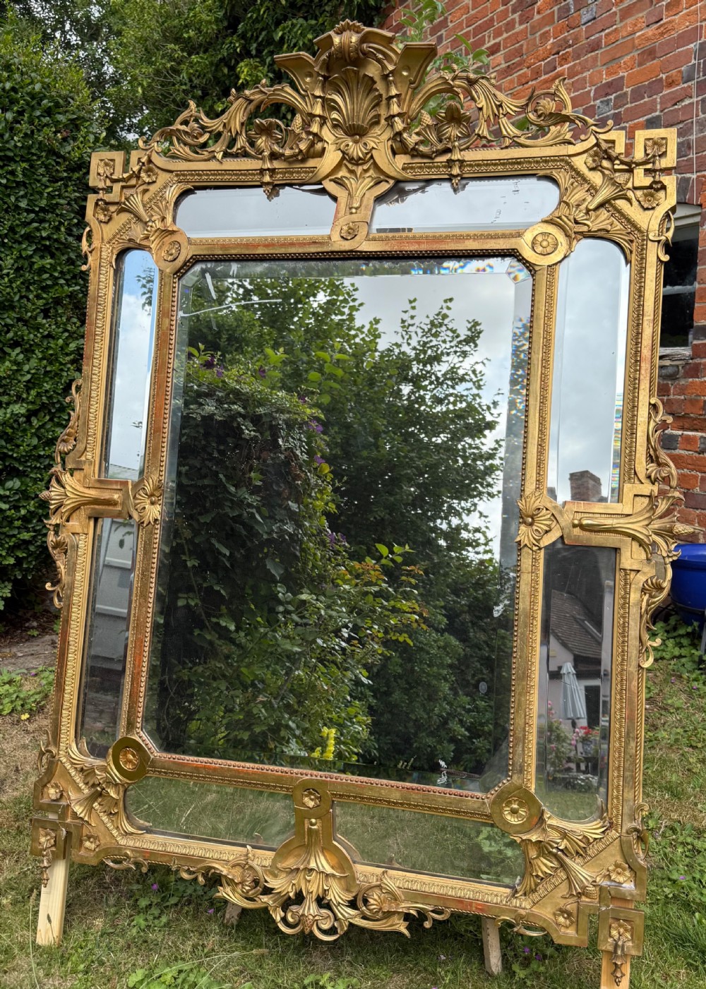 An ornate nineteenth-century French giltwood cushion mirror featuring a central bevelled plate surrounded by border glass panels and elaborate scrollwork cresting. View III