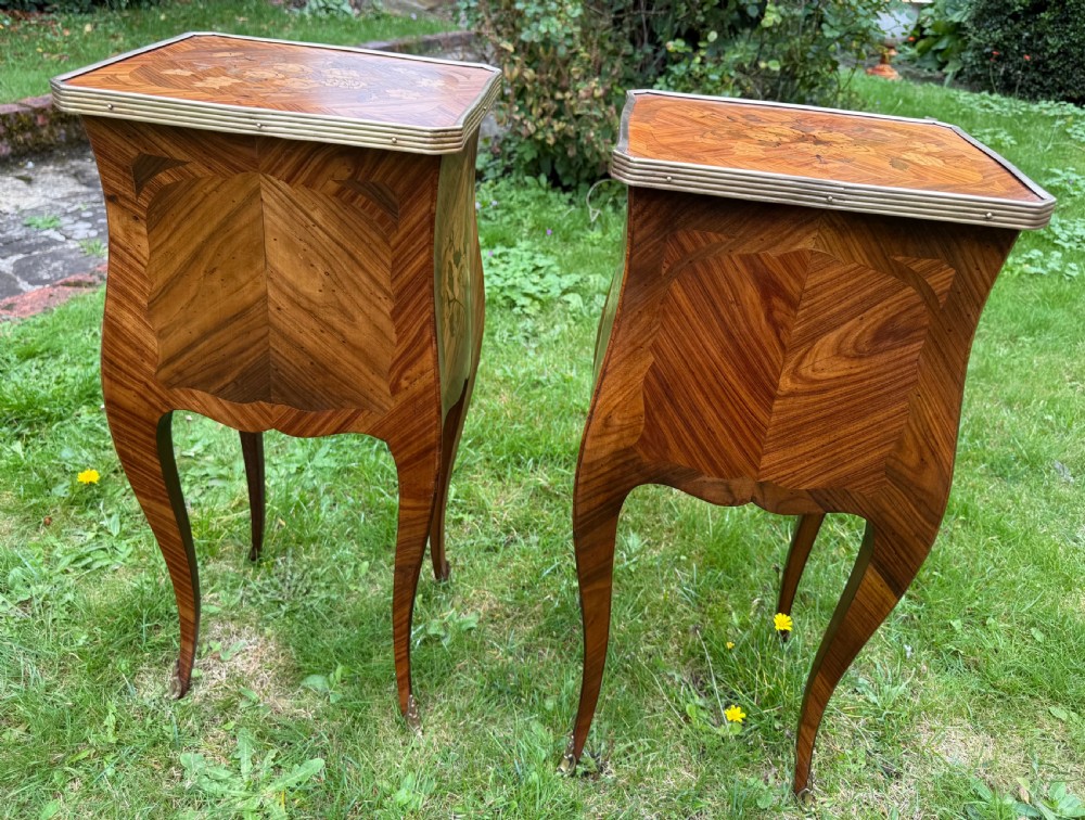 A pair of French Louis XV style marquetry bedside tables with floral wood inlays, brass rimmed tops, twin drawers, and slender cabriole legs. View V