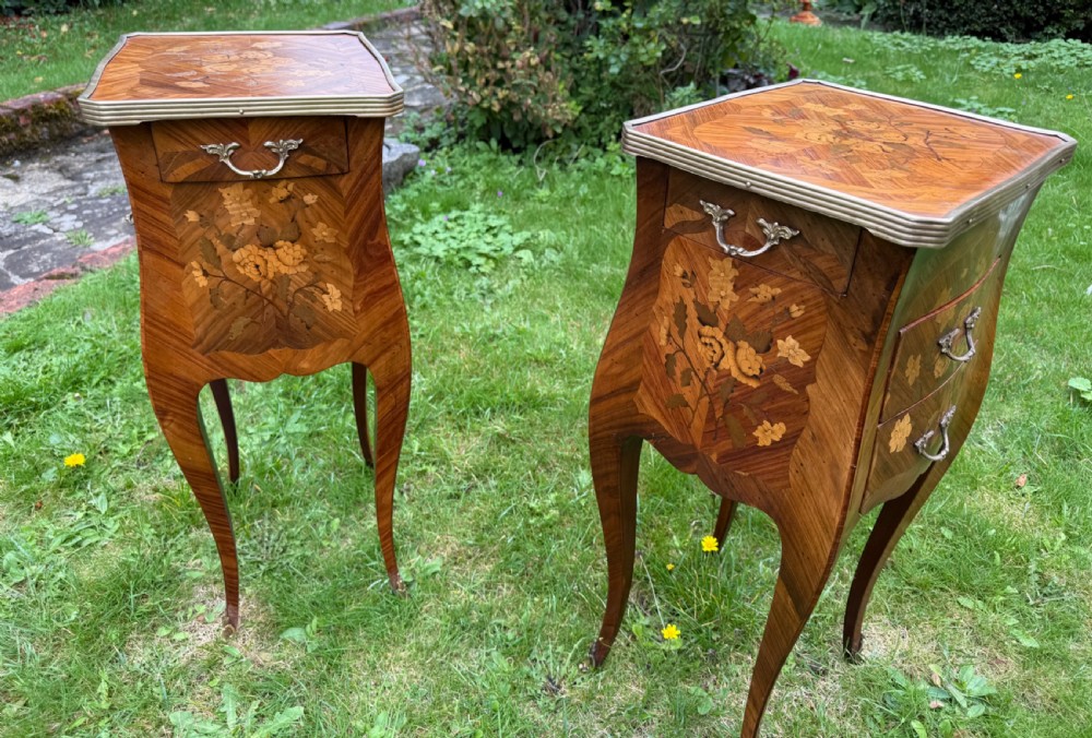 A pair of French Louis XV style marquetry bedside tables with floral wood inlays, brass rimmed tops, twin drawers, and slender cabriole legs. View VI