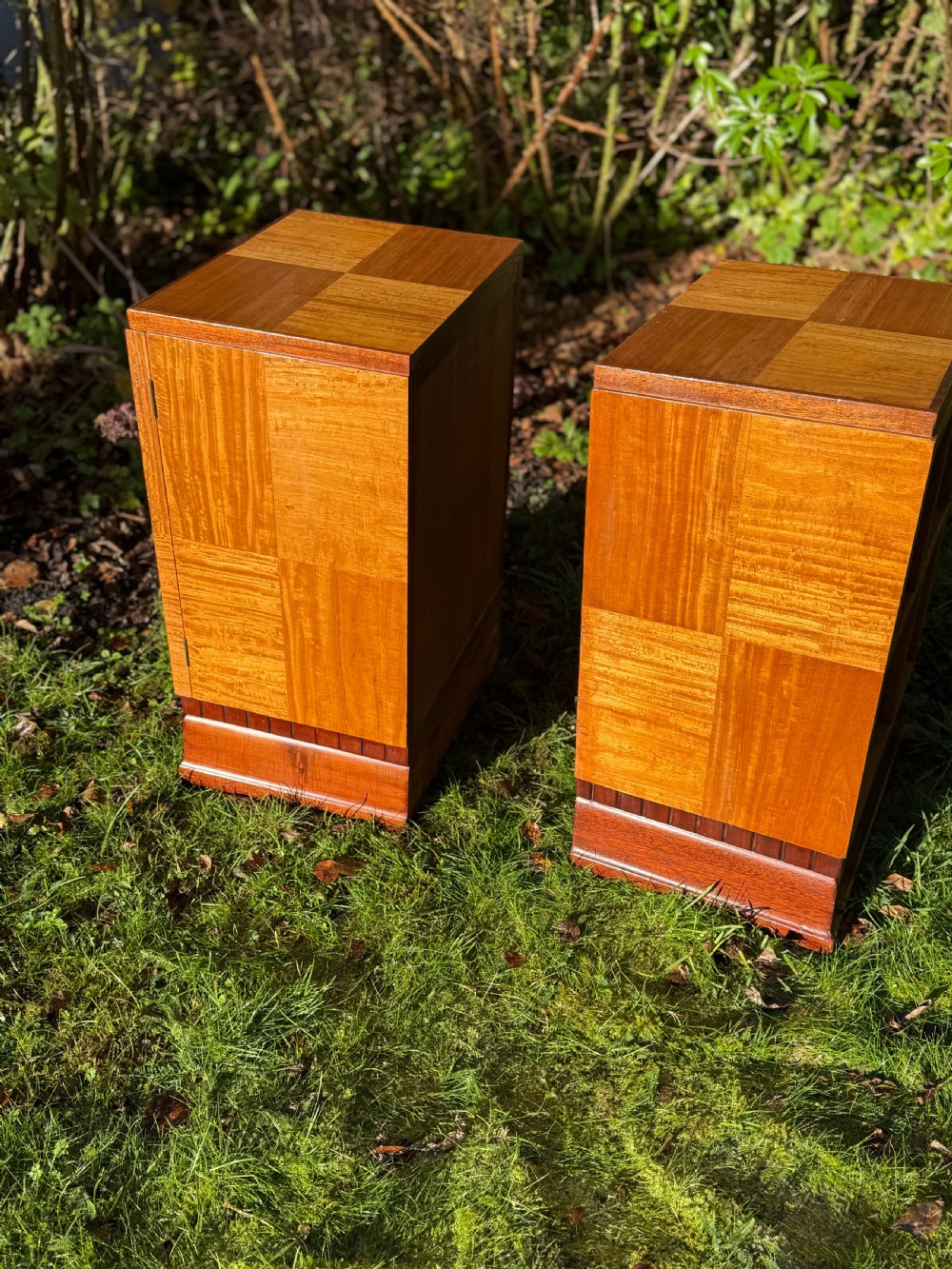 A pair of Art Deco wooden bedside tables featuring checkerboard veneer patterns, with one cabinet unit and one open geometric shelving unit. View IV