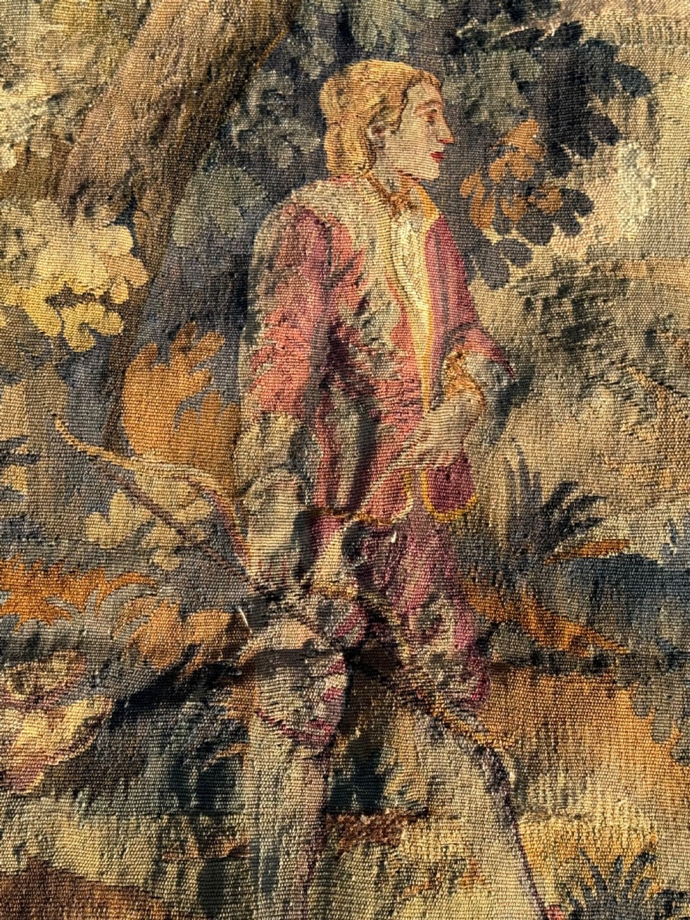 A 19th-century woven wall tapestry depicting a pastoral landscape scene with figures in romantic attire within a detailed floral border. View V